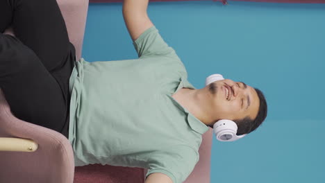 Vertical-video-of-Happy-man-listening-to-music-with-headphones.